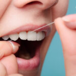 Closeup of a woman flossing her teeth because it is important