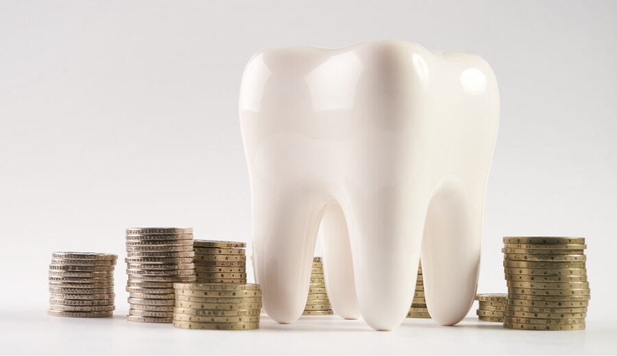 A tooth next to several piles of coins to indicate how to save money on family dental care in Pharr, TX